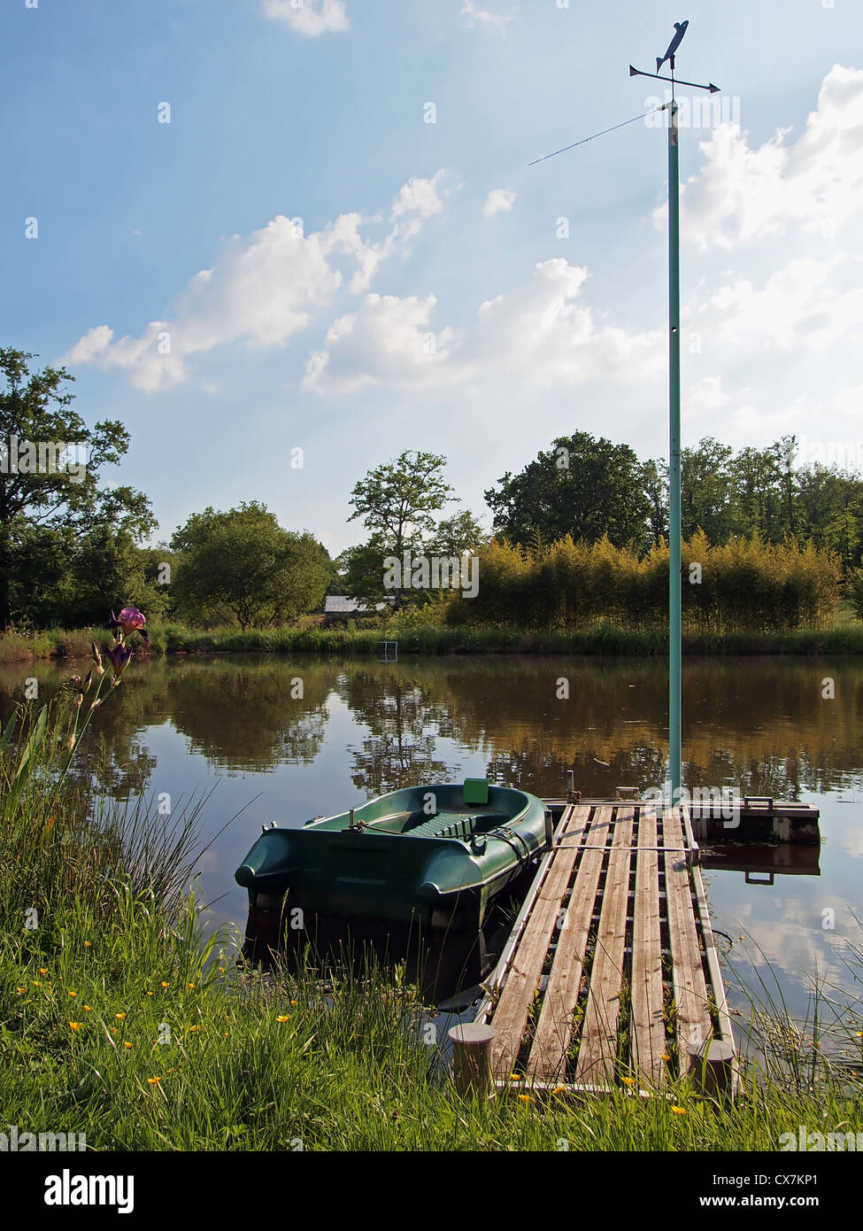 Floating dock on a pond with a small boat and a weather vane Stock Photo