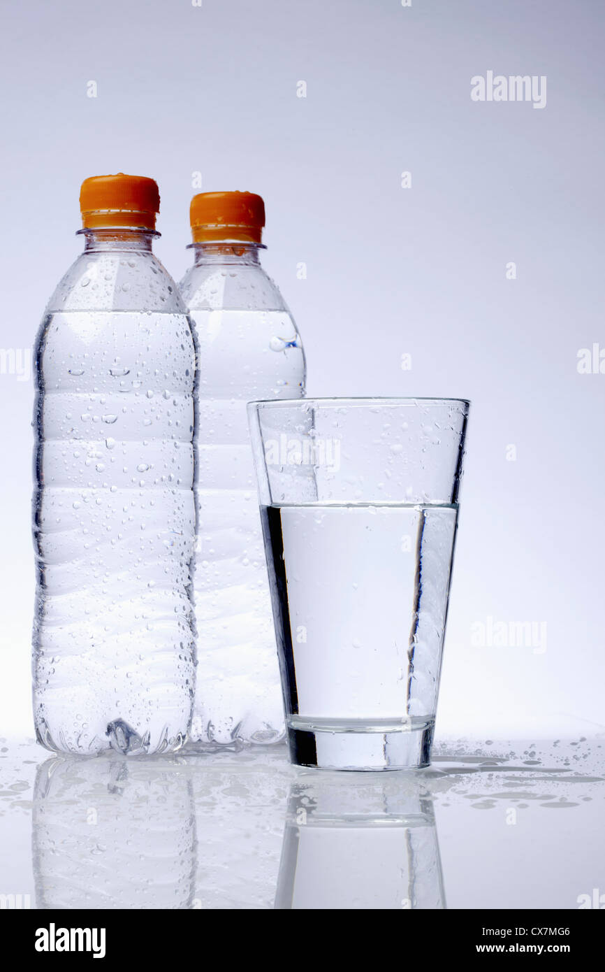 Two full plastic water bottles and a drinking glass Stock Photo