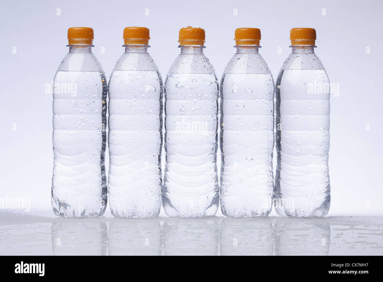 A row of five full plastic water bottles in a row Stock Photo