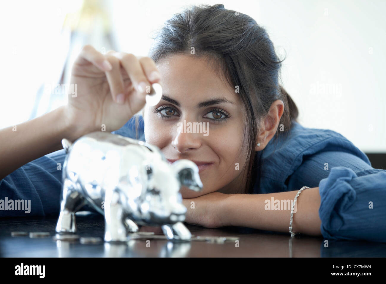 Woman putting coin into piggy bank Stock Photo - Alamy