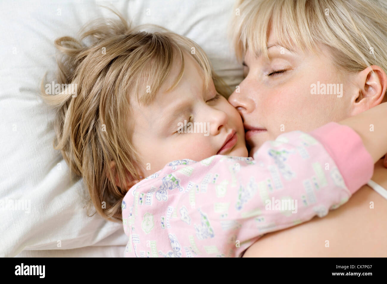 A mother and her young daughter sleeping a bed side by side Stock Photo