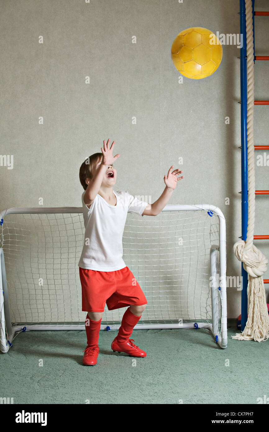 A young boy defending a goal while a ball flies towards him Stock Photo