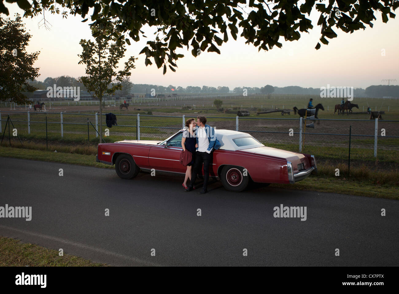 A rockabilly couple leaning against a vintage car in the country Stock Photo