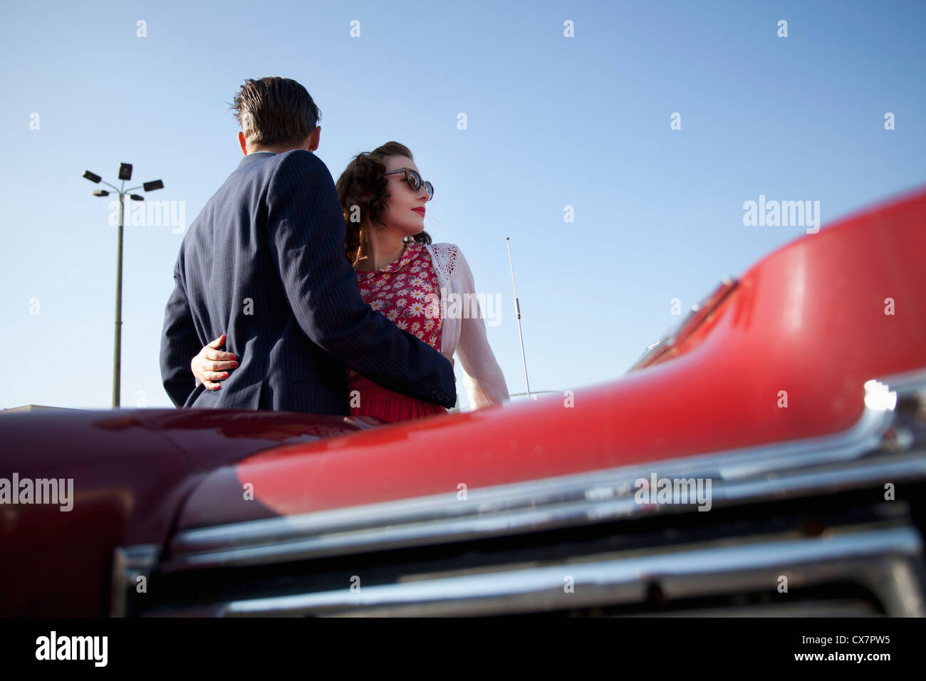 A cool, rockabilly couple with arms around each other by a vintage car Stock Photo