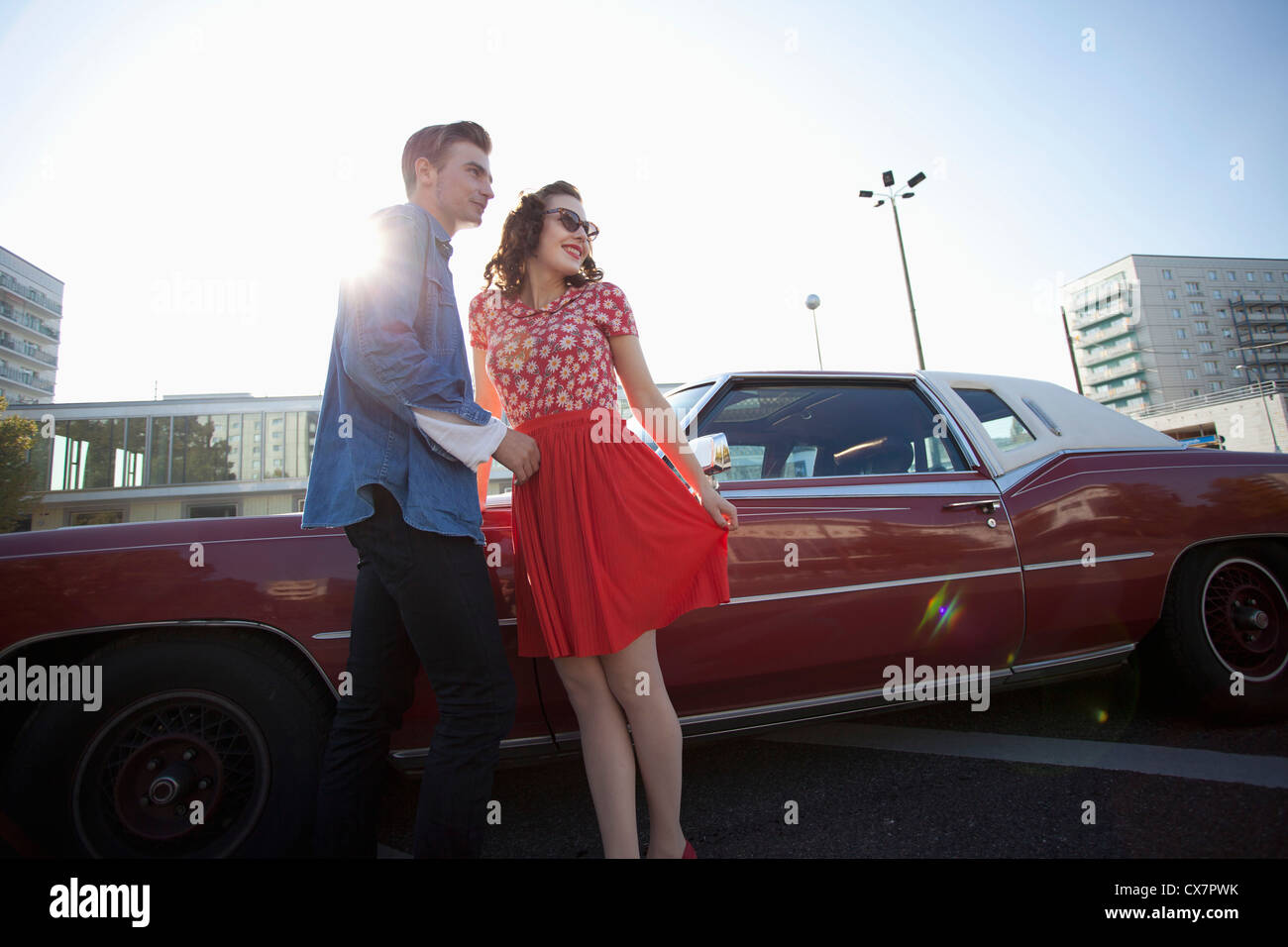 A cheerful rockabilly couple standing next to a vintage car Stock Photo