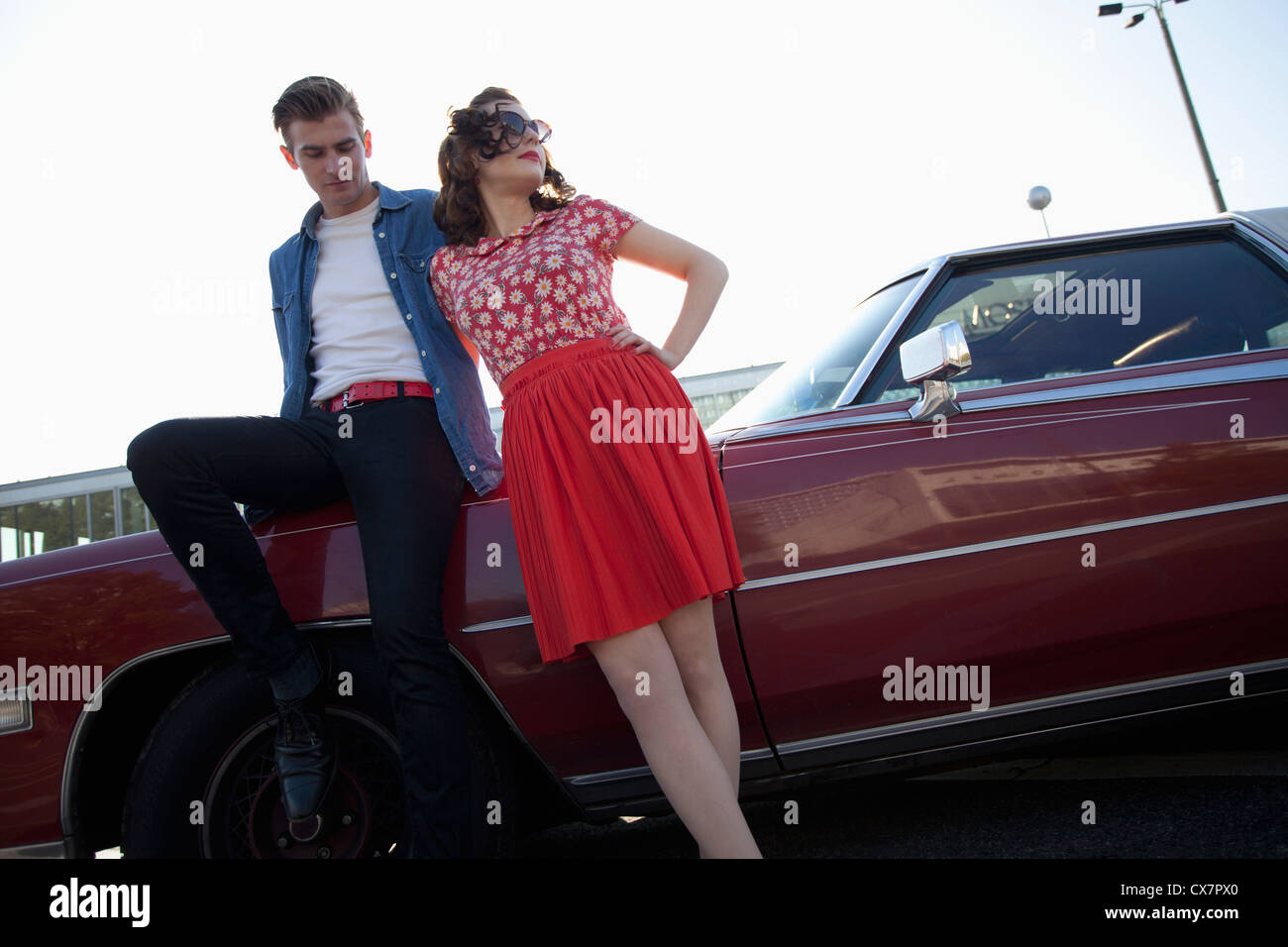 A cool, rockabilly couple leaning against a vintage car Stock Photo