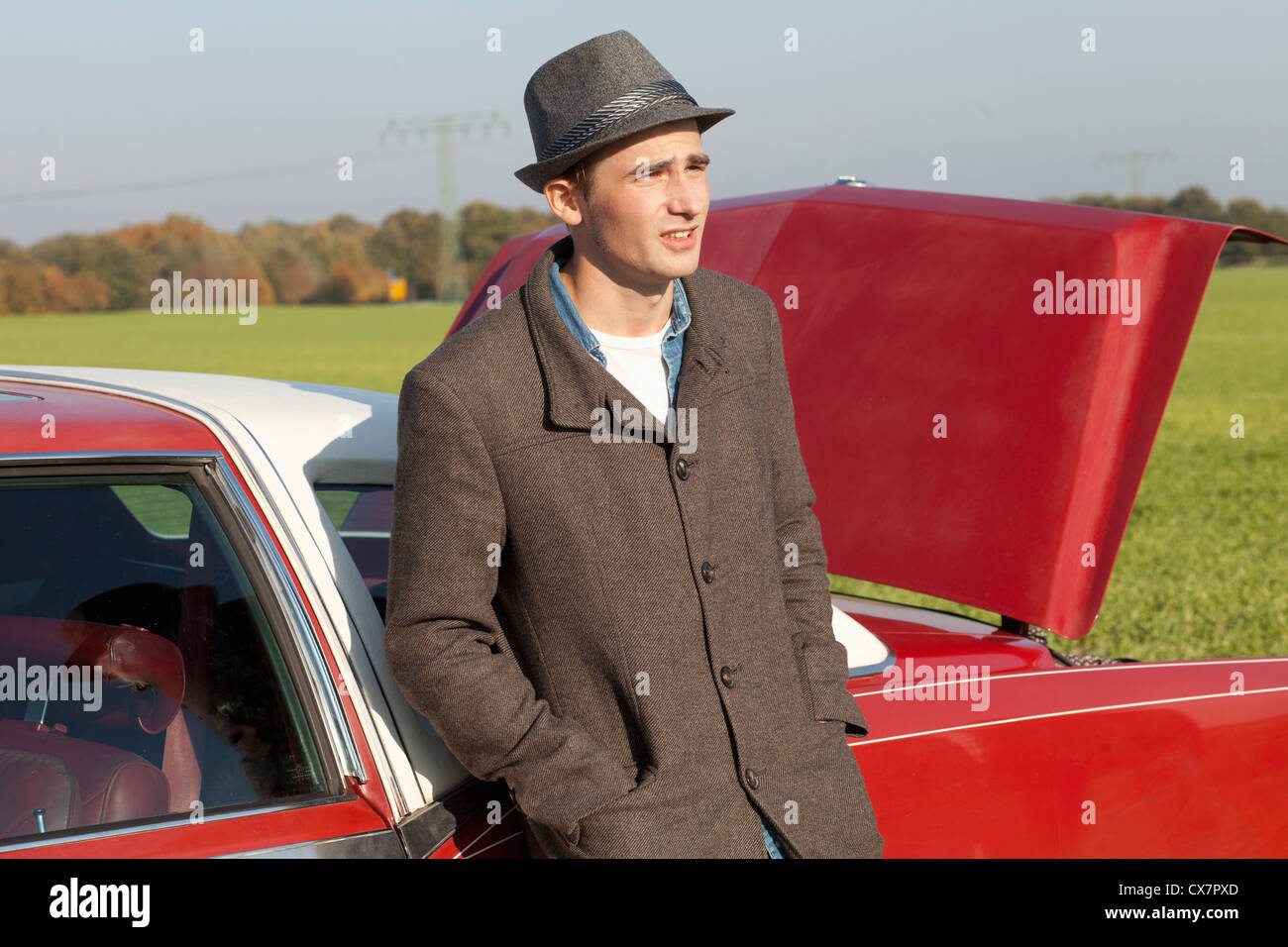 A young rockabilly man leaning against a vintage car in the country Stock Photo