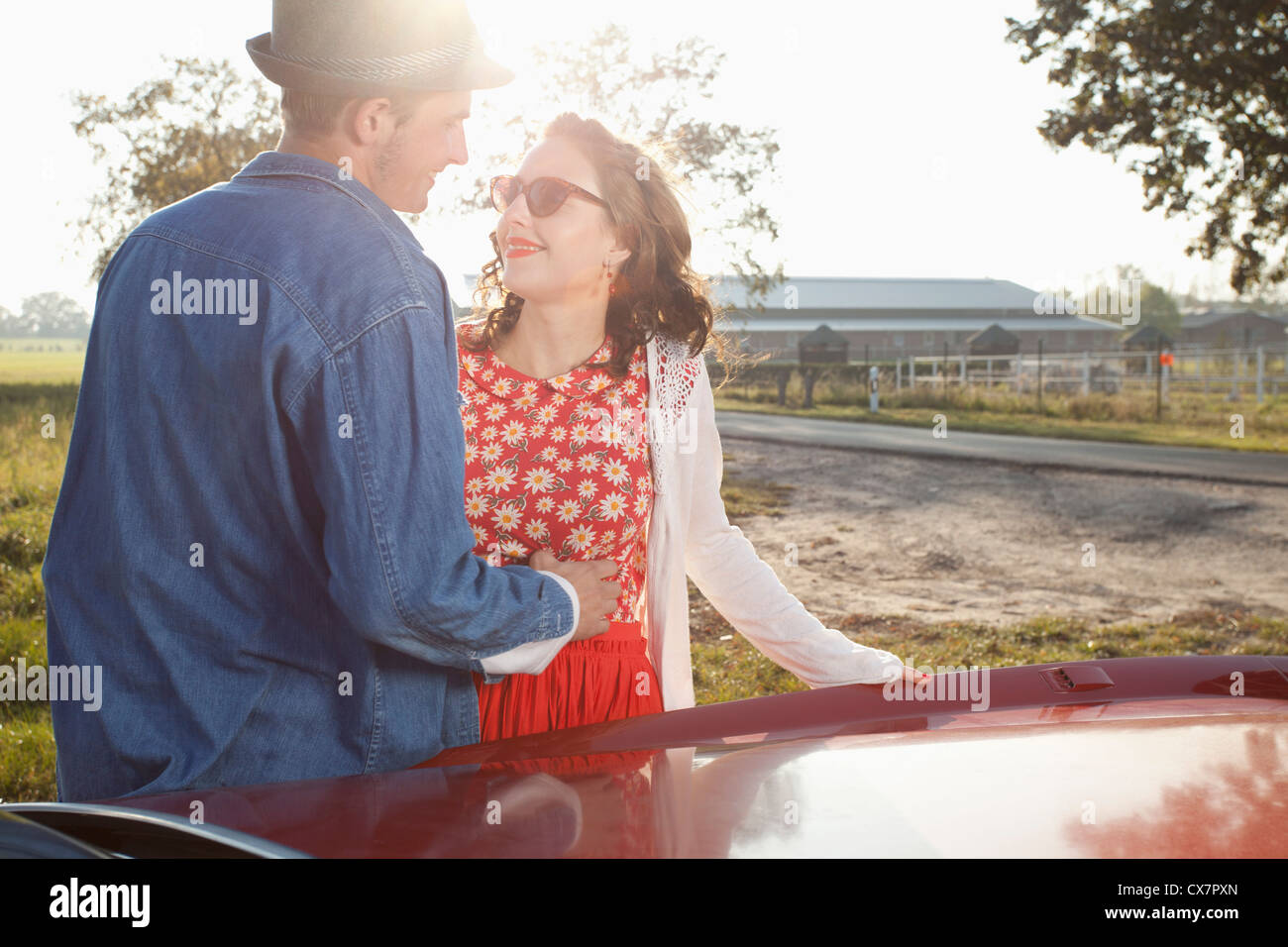 A flirtatious rockabilly couple standing next to a vintage car Stock Photo