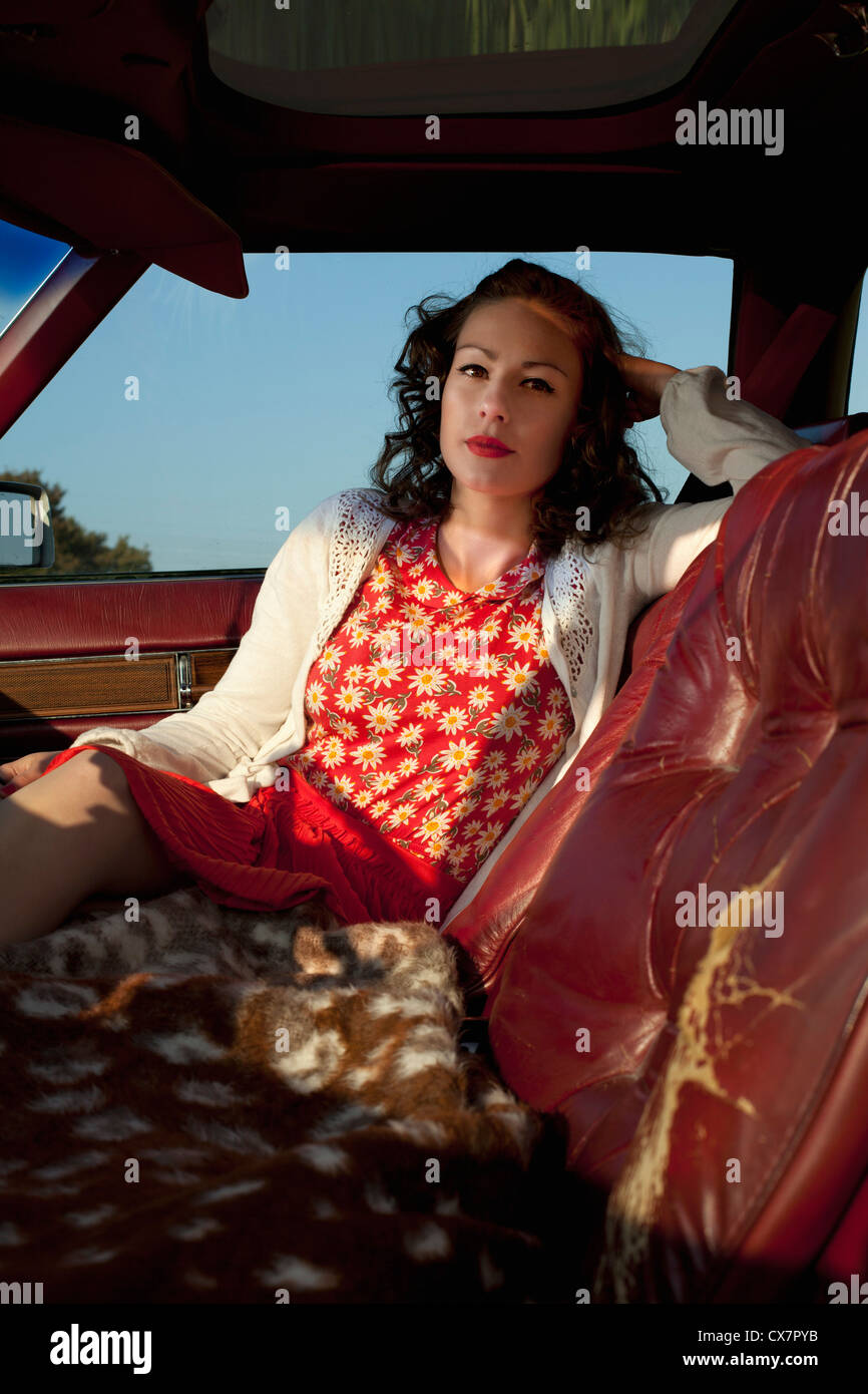 A pretty rockabilly woman sitting in the passenger seat of a vintage car Stock Photo