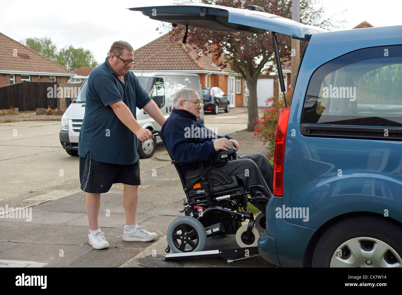 Male Carer son pushing a disabled elderly man in a wheelchair onto a