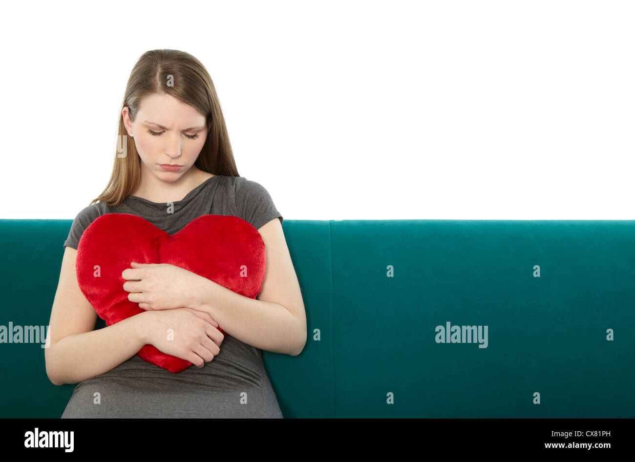 Woman cuddling with a heart pillow Stock Photo