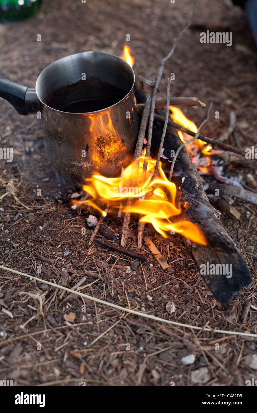 Burning wood at campfire, with flames and black coffee pot Stock Photo Alamy