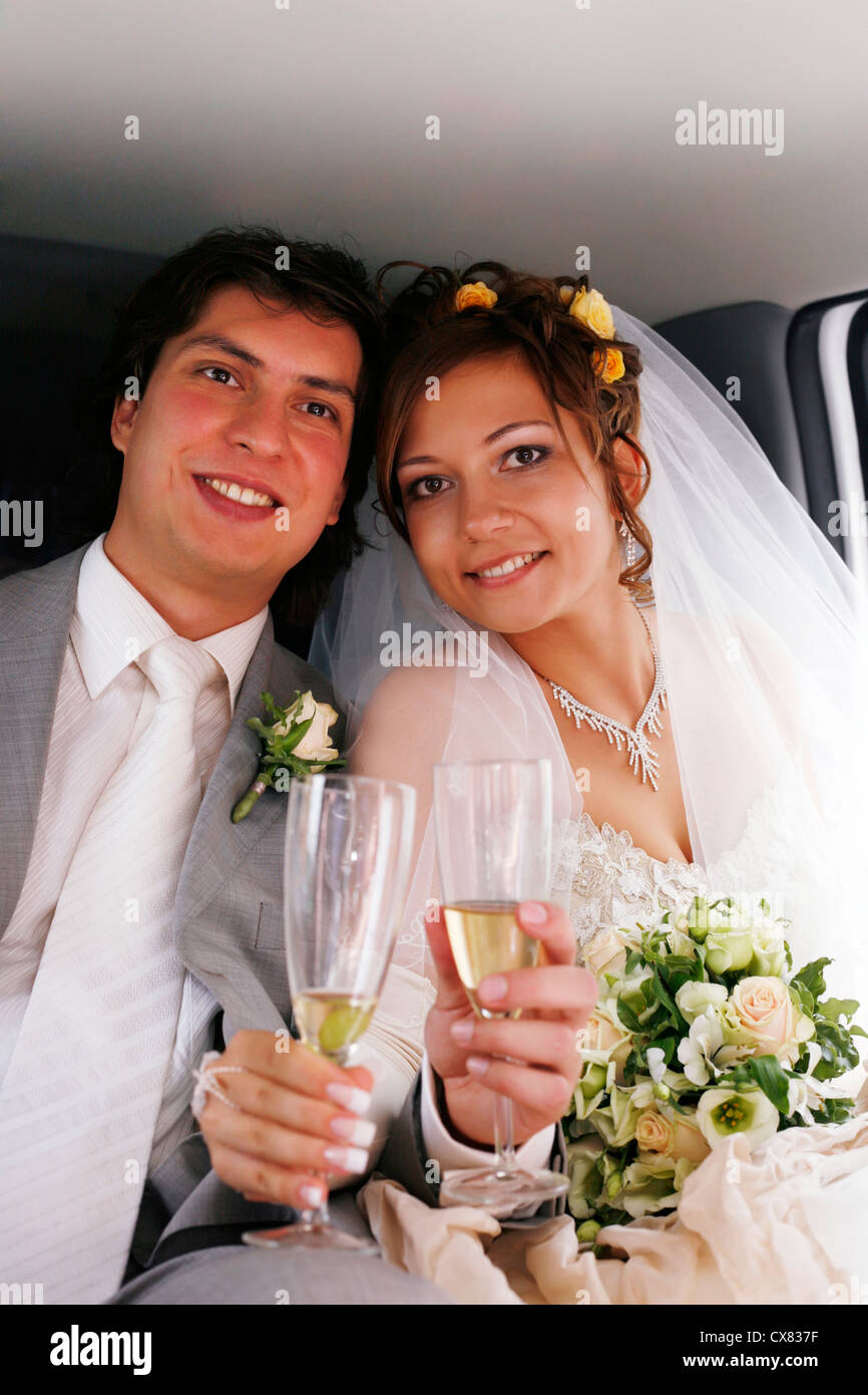 The bride with the groom drinks champagne in the automobile Stock Photo