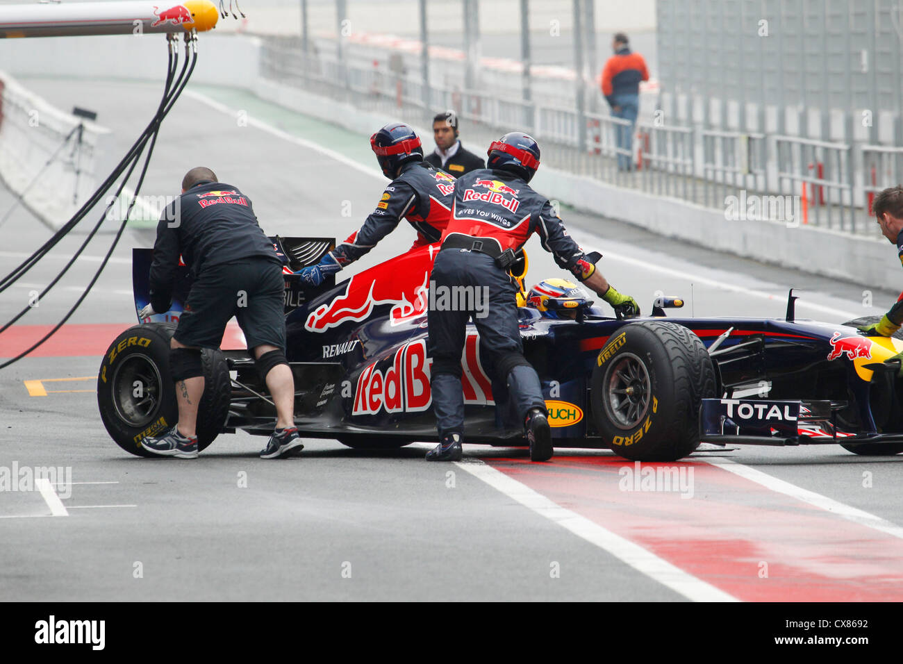 Mark Webber being pushed back by Red Bull mechanics into pit garage during testing at Montmelo racing track in Barcelona, Spain Stock Photo