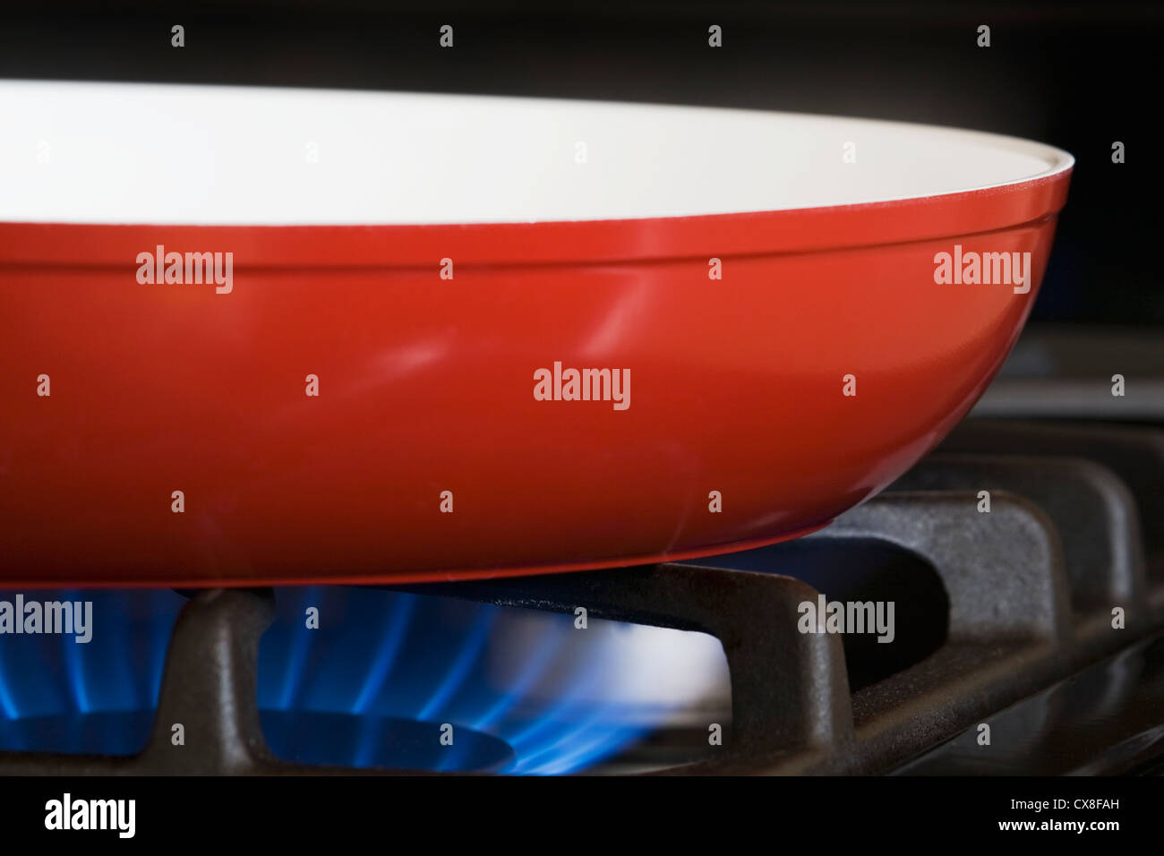 Close Up Of A Red Frying Pan On A Gas Stove With Blue Gas Burner