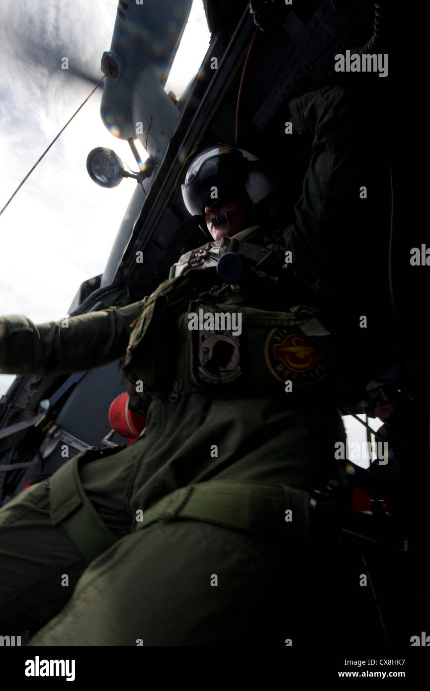 Naval Aircrewman 2nd Class William Branson lowers a basket during a search and rescue exercise from an MH-60S Sea Hawk helicopter, assigned to Helicopter Sea Combat Squadron (HSC) 25. HSC 25 is currently underway with the forward-deployed amphibious assault ship USS Bonhomme Richard (LHD 6), the lead ship of the only forward-deployed amphibious ready group. Stock Photo