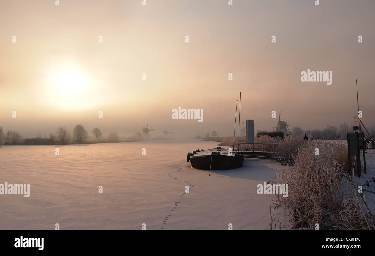 Sunrise in winter over a frozen canal and windmills at the famous dutch UNESCO site Kinderdijk, Holland. Stock Photo