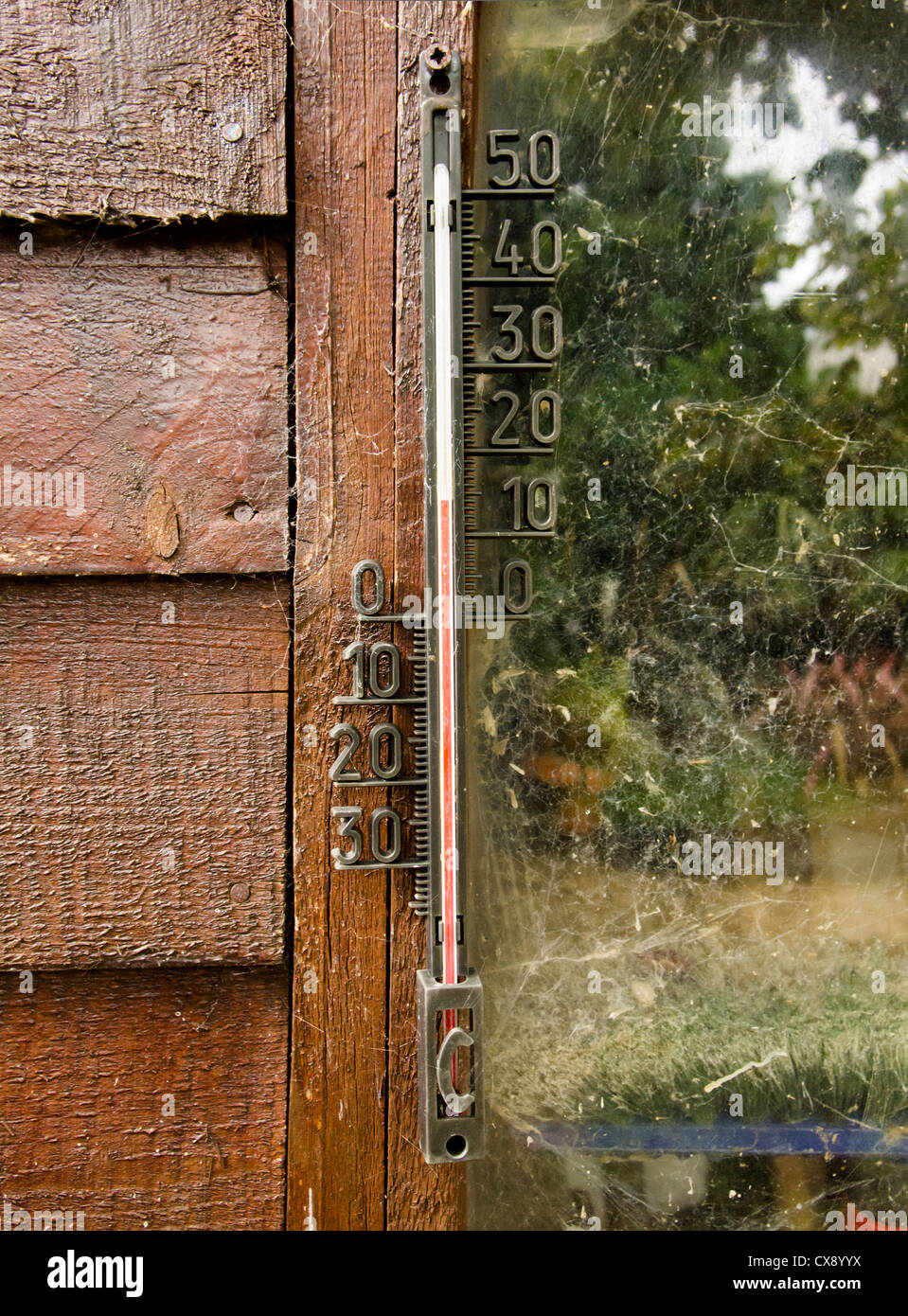 An outdoor thermometer hanging on the wall of a wooden garden shed Stock Photo