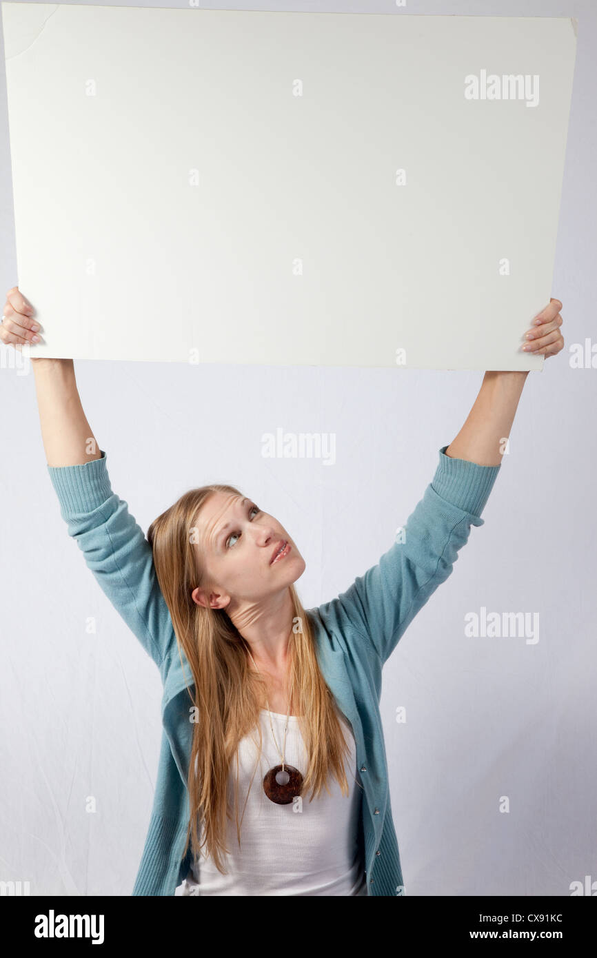 Pretty blond woman, holding a blank sign for your message to be imprinted on Stock Photo