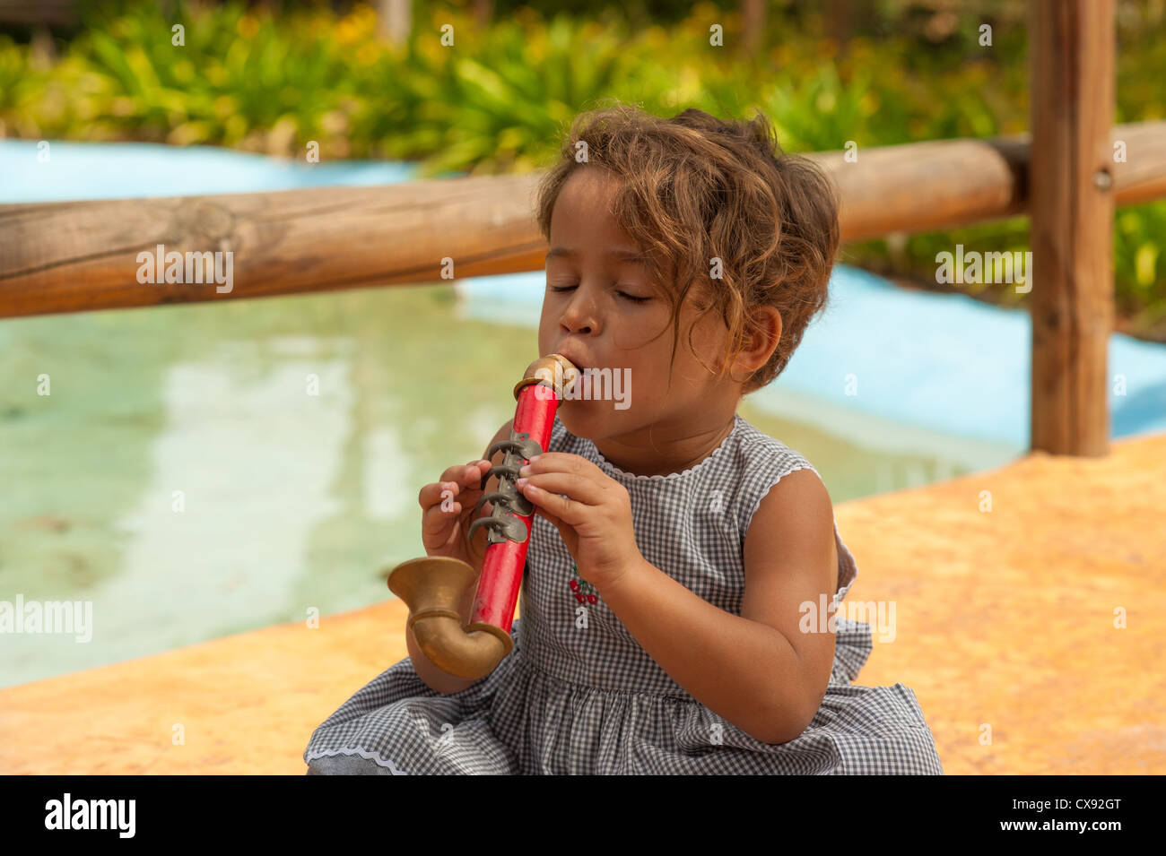 Cute Hispanic girl playing with a toy saxophone Stock Photo