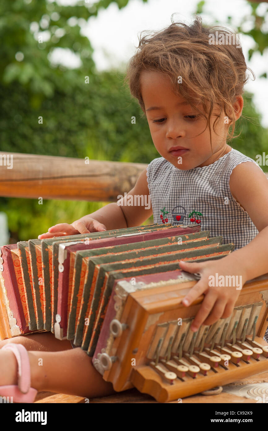 Cute girl playing with a vintage accordion Stock Photo