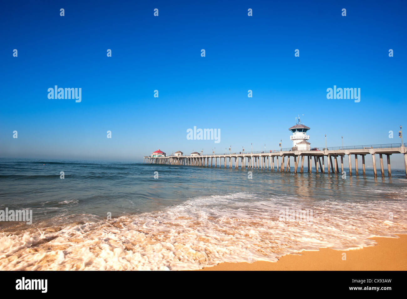 Huntington Beach Pier during early morning shows the tides changing with rushing surf moving up the shoreline. Stock Photo