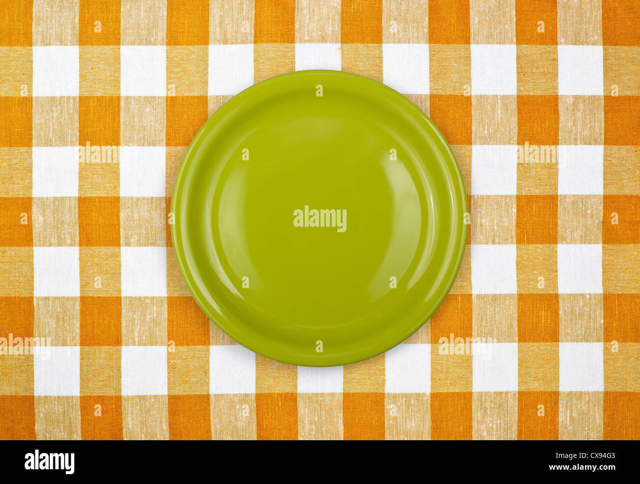 green plate on yellow checked tablecloth Stock Photo