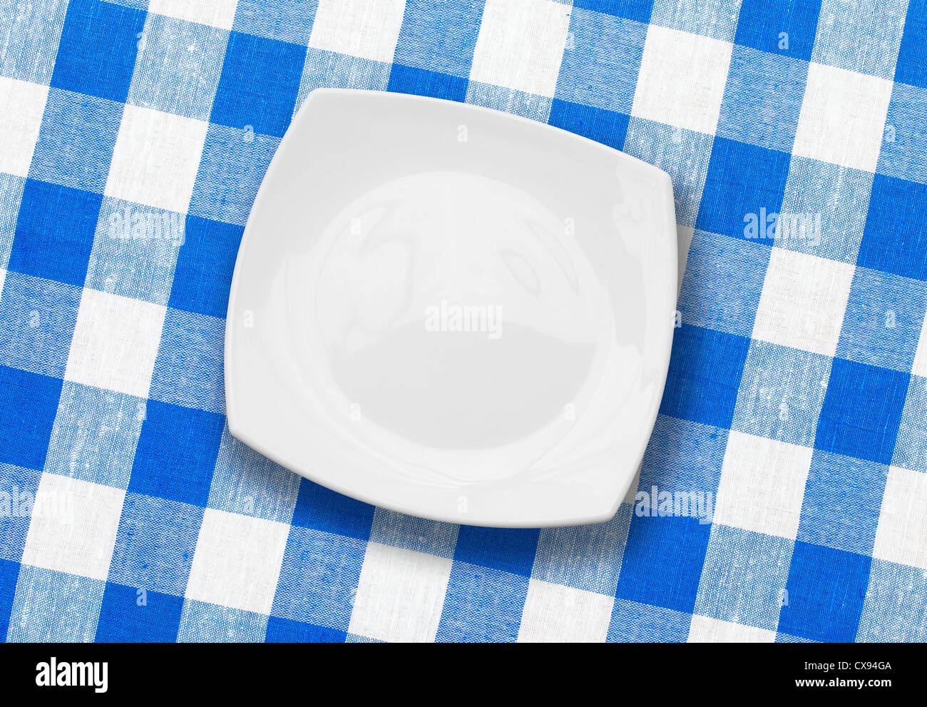 white plate on blue checked fabric tablecloth Stock Photo