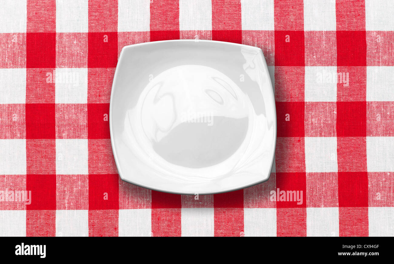 white plate on red checked fabric tablecloth Stock Photo