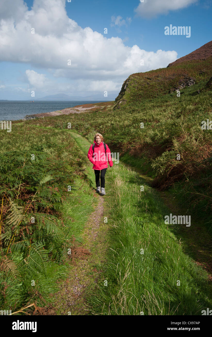 Front View Of A Woman Person Walking Through The Countryside Wearing Waterproof Clothing and A Rucksack Stock Photo
