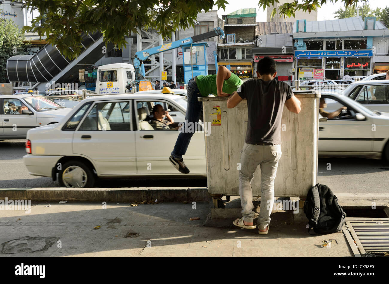 Young men searching inside a wheelie bin in Tajrish, north of Tehran, Iran Stock Photo