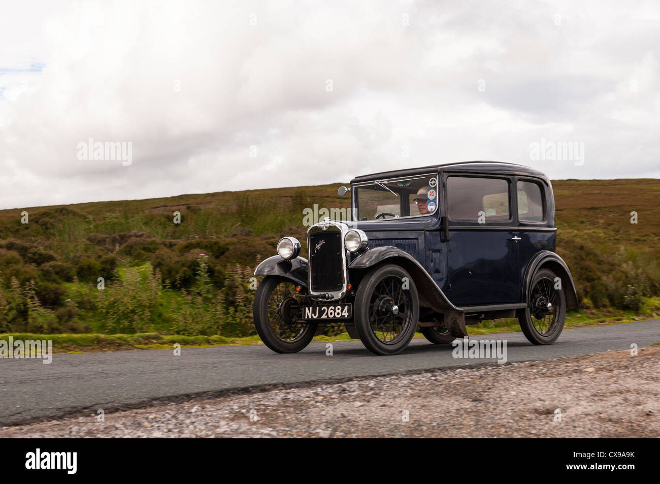 A vintage Austin 7 classic car driving through the Yorkshire Dales showing movement in Yorkshire , England , Britain , Uk Stock Photo