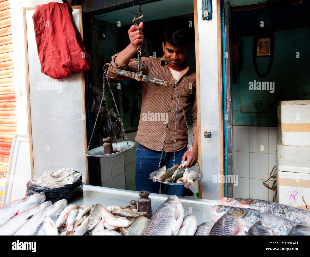 Nepali man selling and weighing fish in a shop, Kathmandu, Nepal Stock Photo