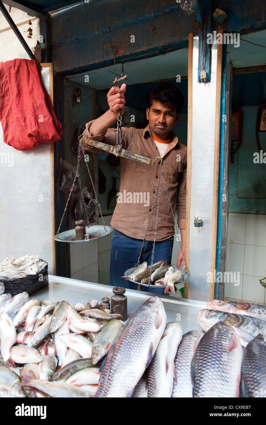 Nepali man selling and weighing fish in a shop, Kathmandu, Nepal Stock Photo