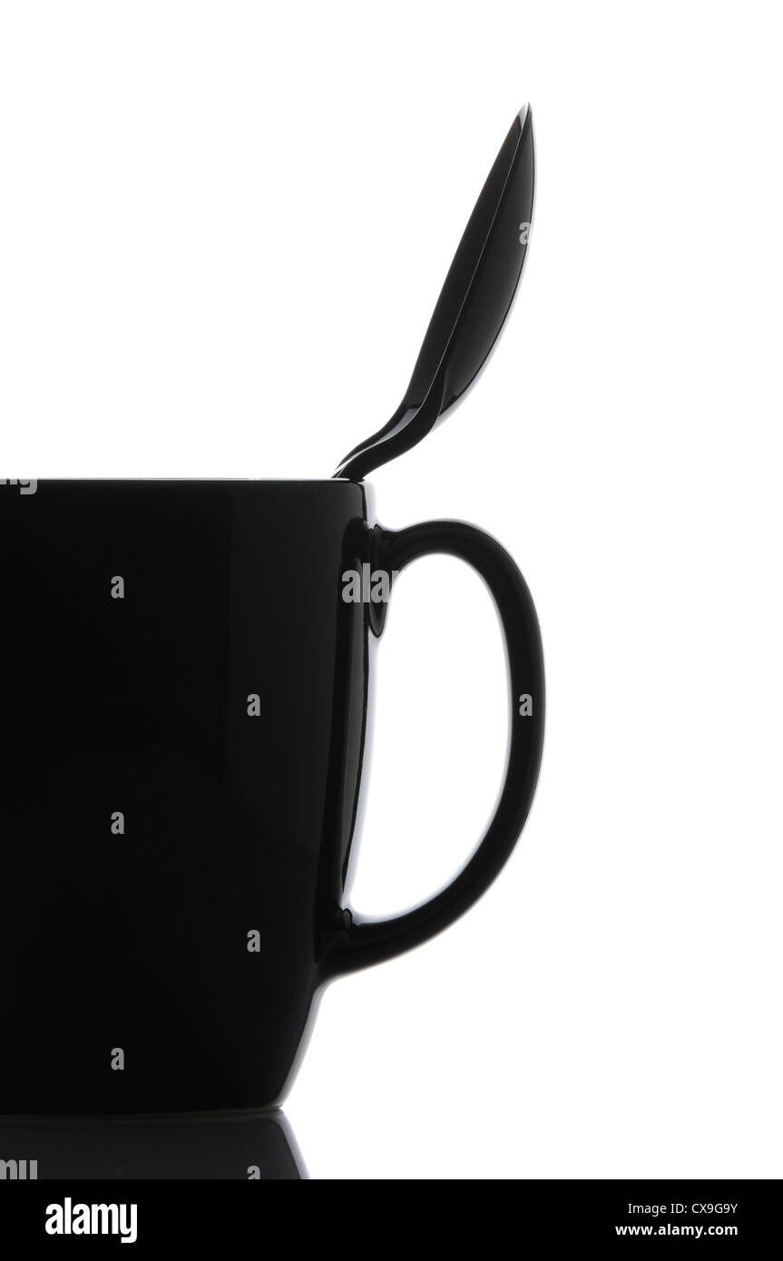 Close up of a black coffee mug with spoon over a white background. Spoon is inside cup leaning on the handle side. Stock Photo