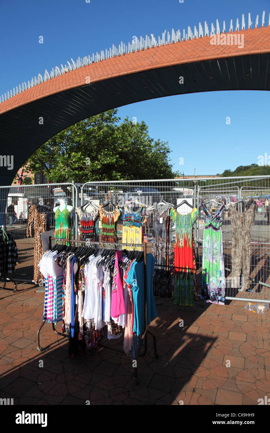 Colorful clothes hang below the Civic Heart sculpture in Chester le Street open air market north east England UK Stock Photo