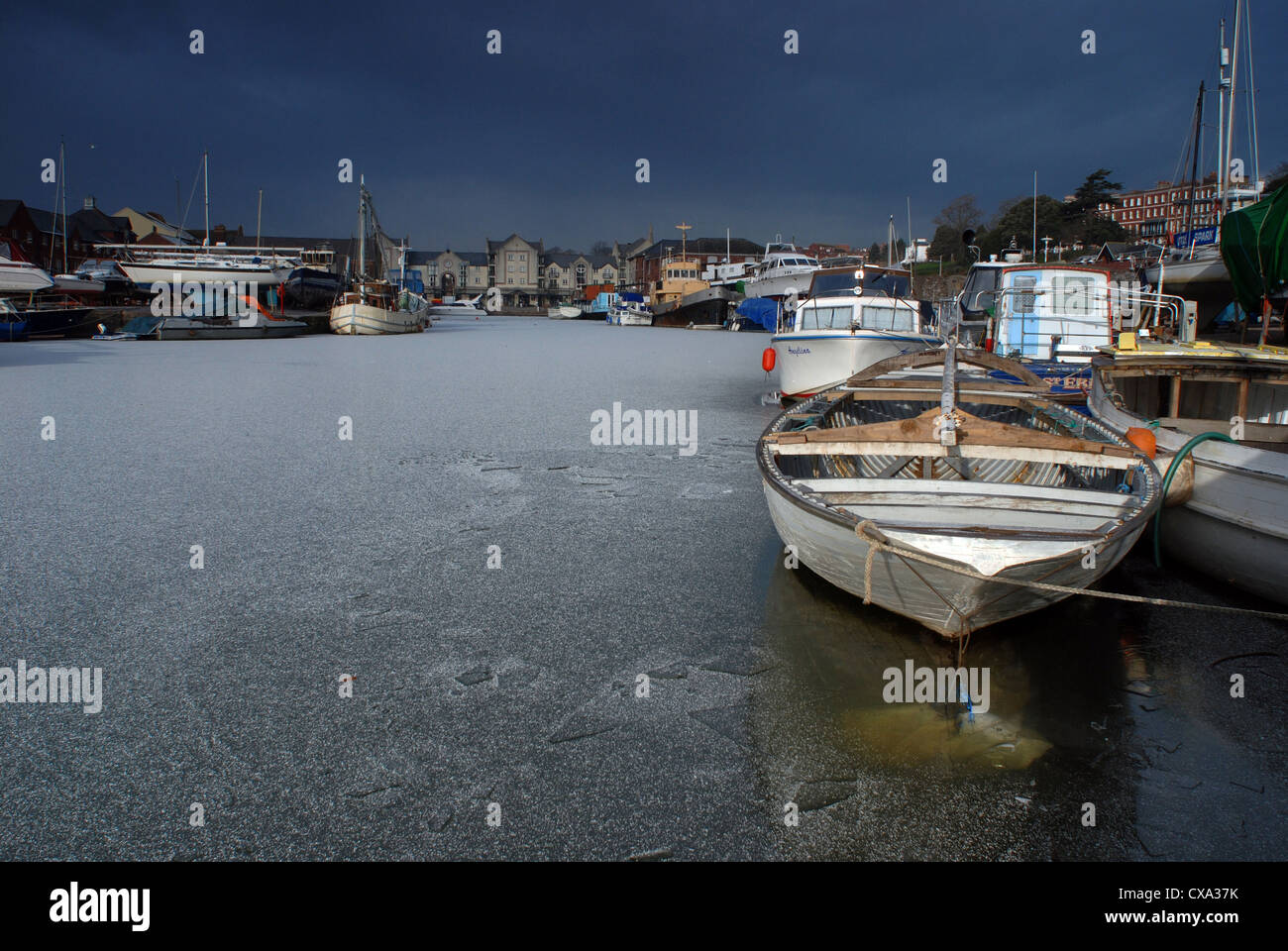 Boats trapped in ice as the Exeter canal basin is covered in a layer of ice. Stock Photo