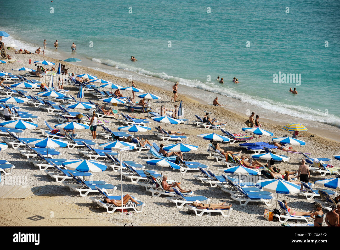 vacationers take in the summer sun on the beach of Albir,Costa Blanca, Spain Stock Photo
