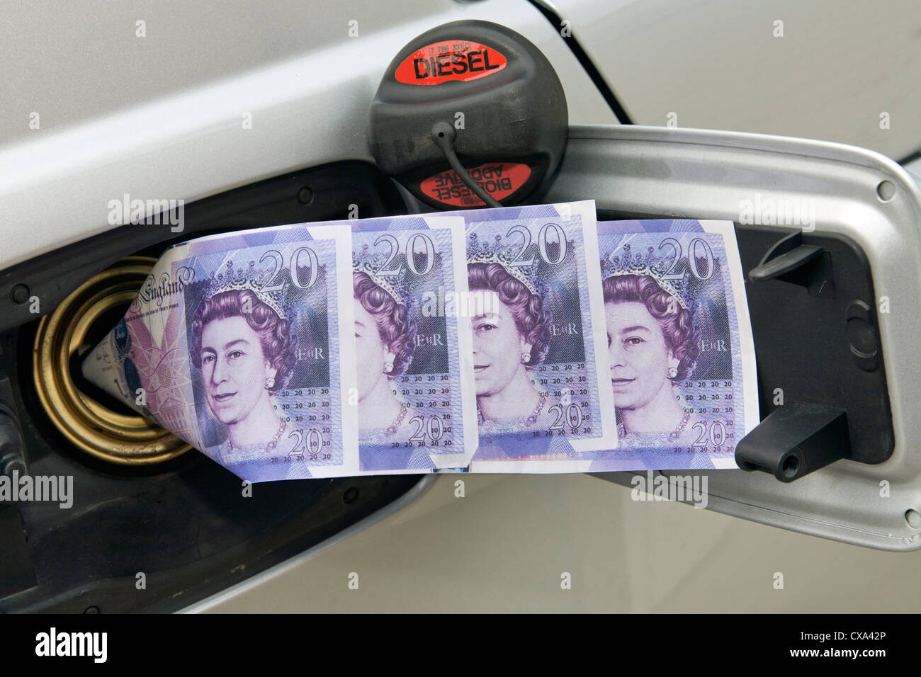 £20 notes going into car fuel tank. Stock Photo