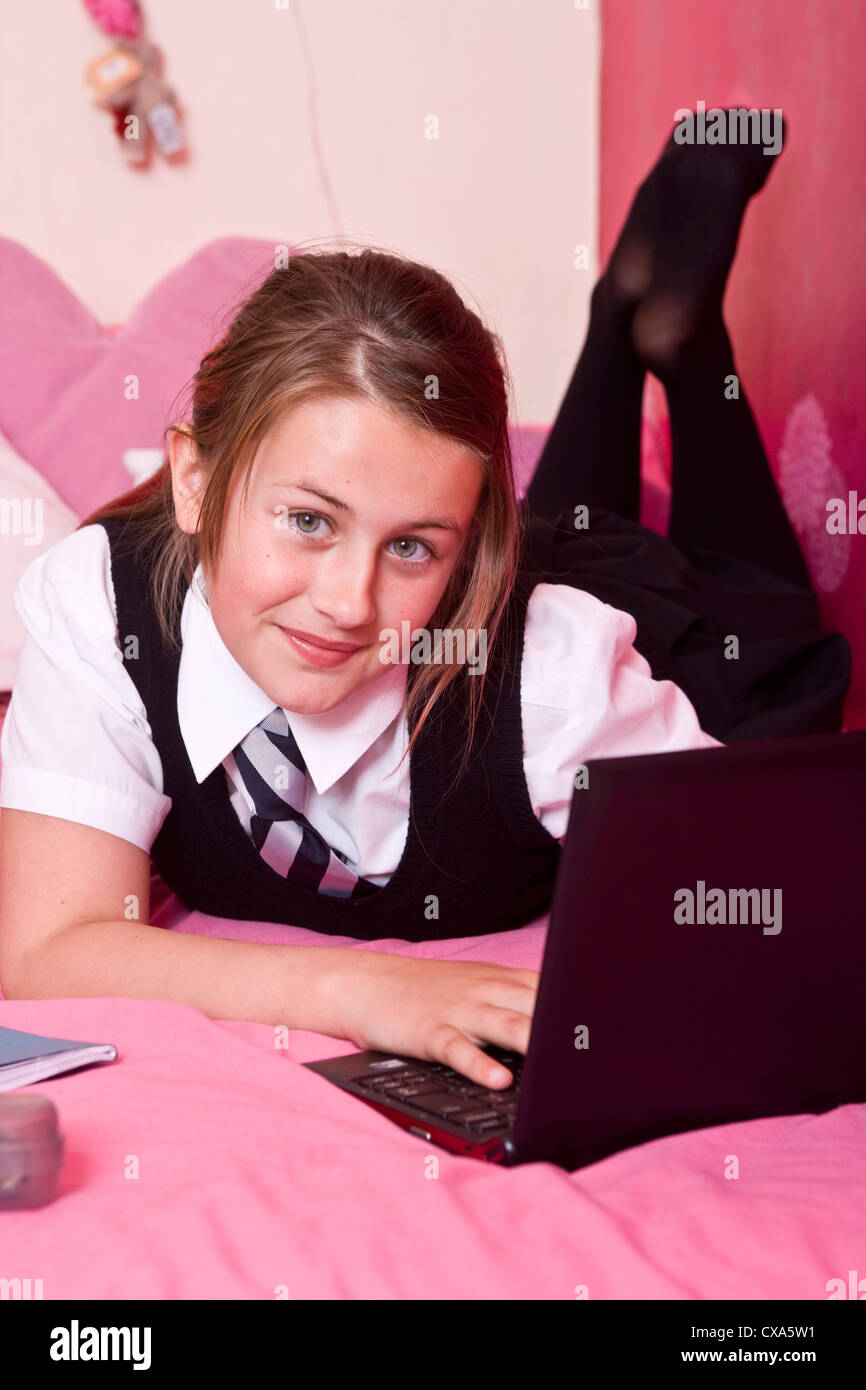 Twelve year old girl lying on her bed using a laptop. Stock Photo