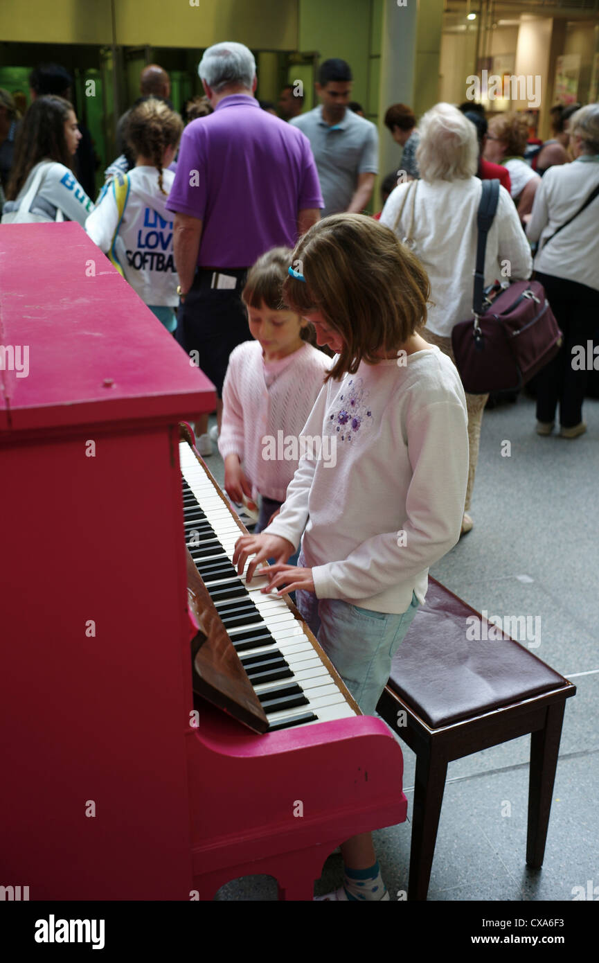 A child plays the public piano at St Pancras train station, London UK Stock Photo