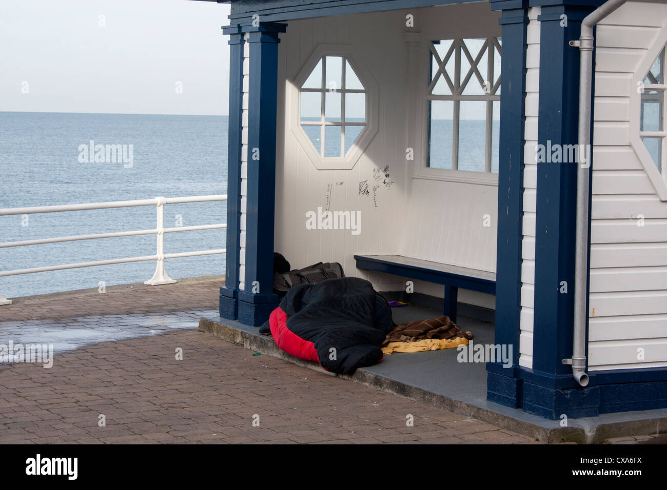 Homeless woman (hidden lying under sleeping bag) sleeping in shelter on