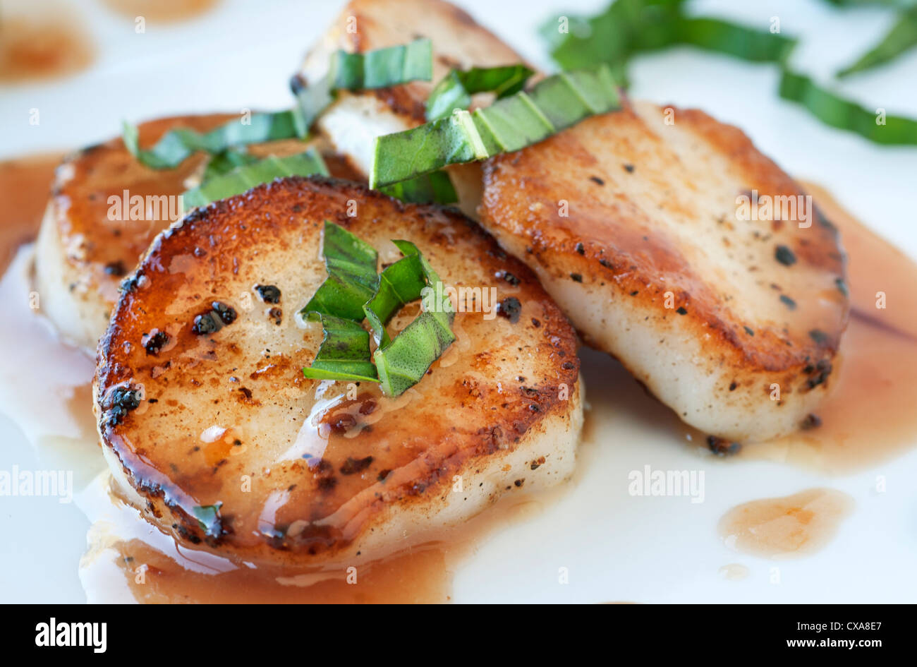 Fresh scallop appetizer with plum sauce and basil Stock Photo