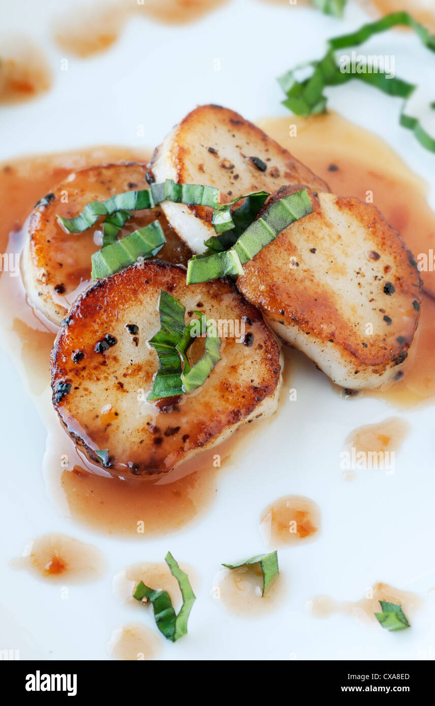 Fresh scallop appetizer with plum sauce and basil Stock Photo