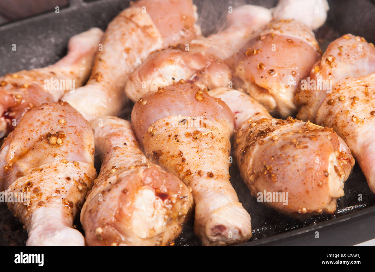 some juicy raw chicken drumstick on frying pan Stock Photo