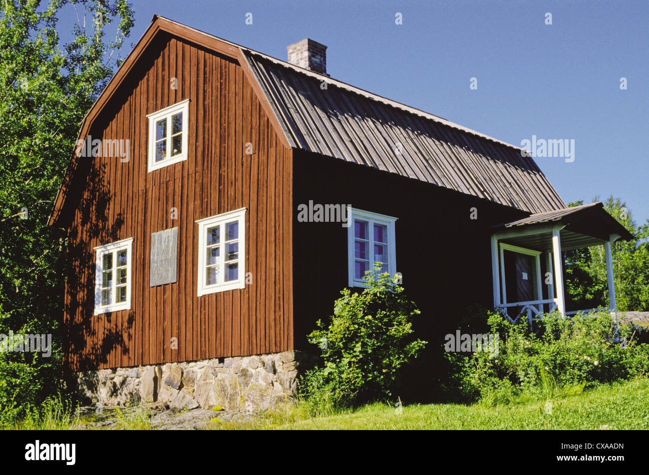 A wood sided home with a stone foundation and a gambrel roof in Palojoki, Finland.  It is the birthplace of Finnish author Aleksis Kivi. Stock Photo