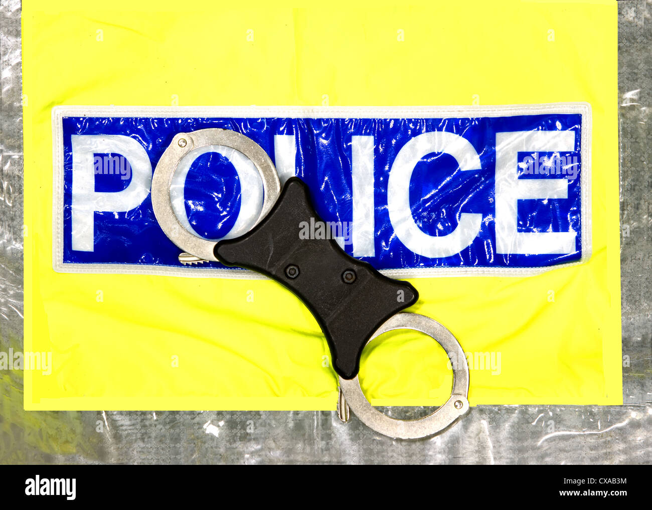 police hand cuffs and a yellow high visibility jacket Stock Photo