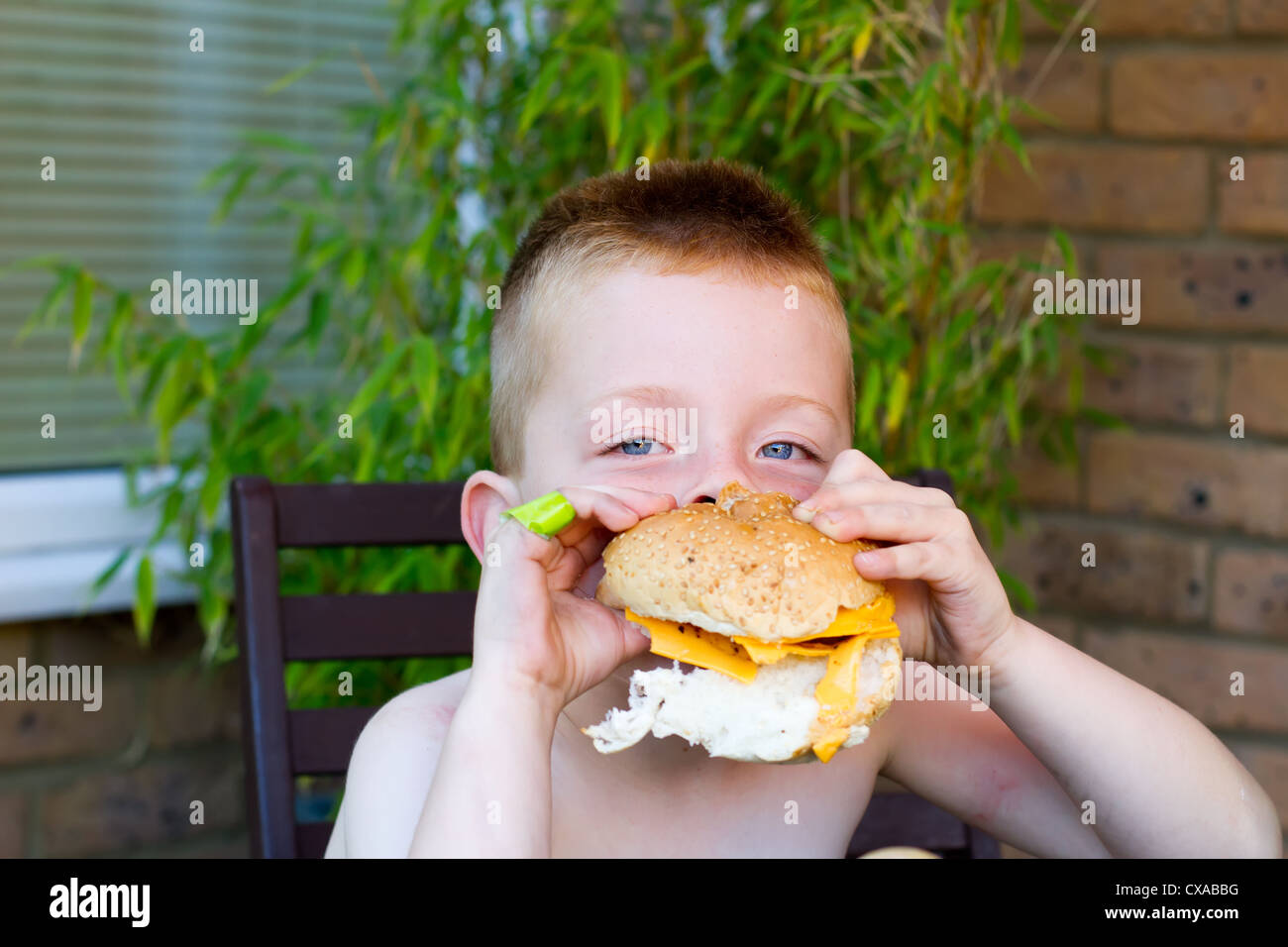 little boy eating a huge burger Stock Photo