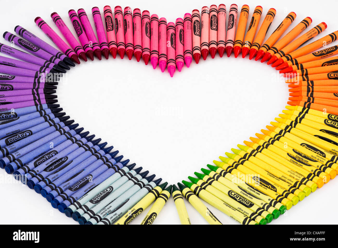 Colourful wax crayons in a heart shape on white background Stock Photo