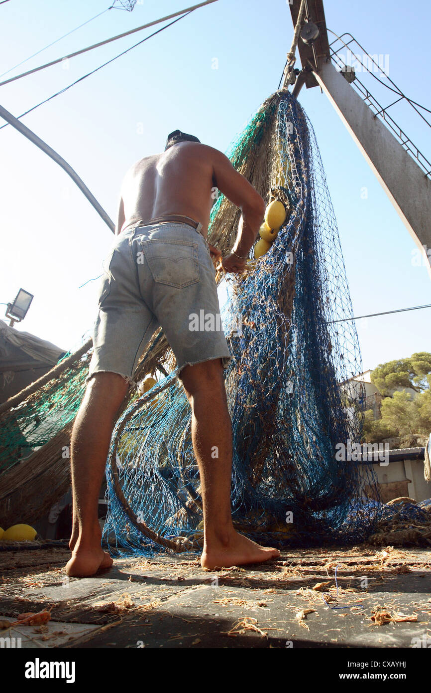 Cala Figuera, fisherman cleans a fishing net Stock Photo